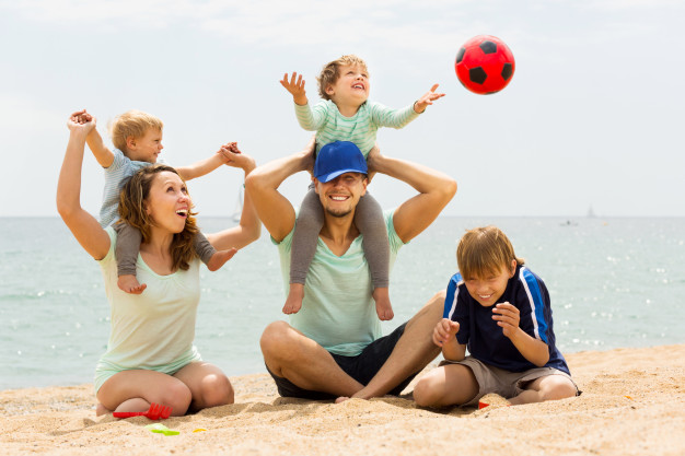 positive-family-of-five-playing-at-sea-beach_1398-4074